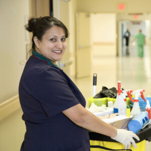 Custodian janitor in hospital hallway with cart