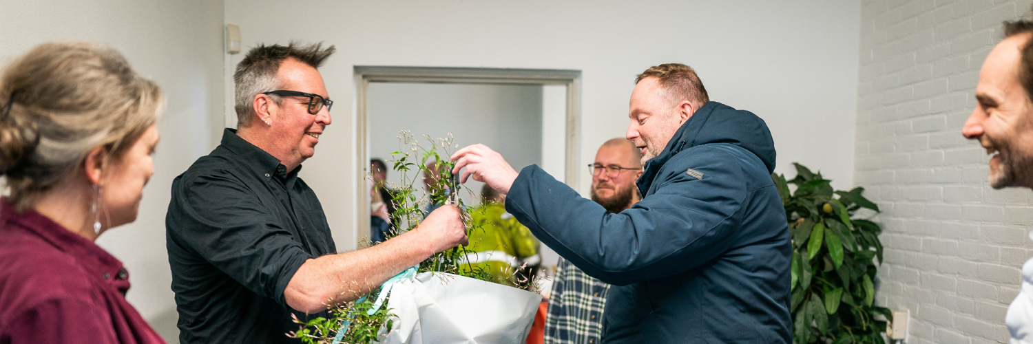 Wethouder Maurits van de Geijn geeft een plant aan Kees Nijdam werkbegeleider van dak en thuislozen De Brug bij de opening van de nieuwe locatie Nieuwe Haven 23